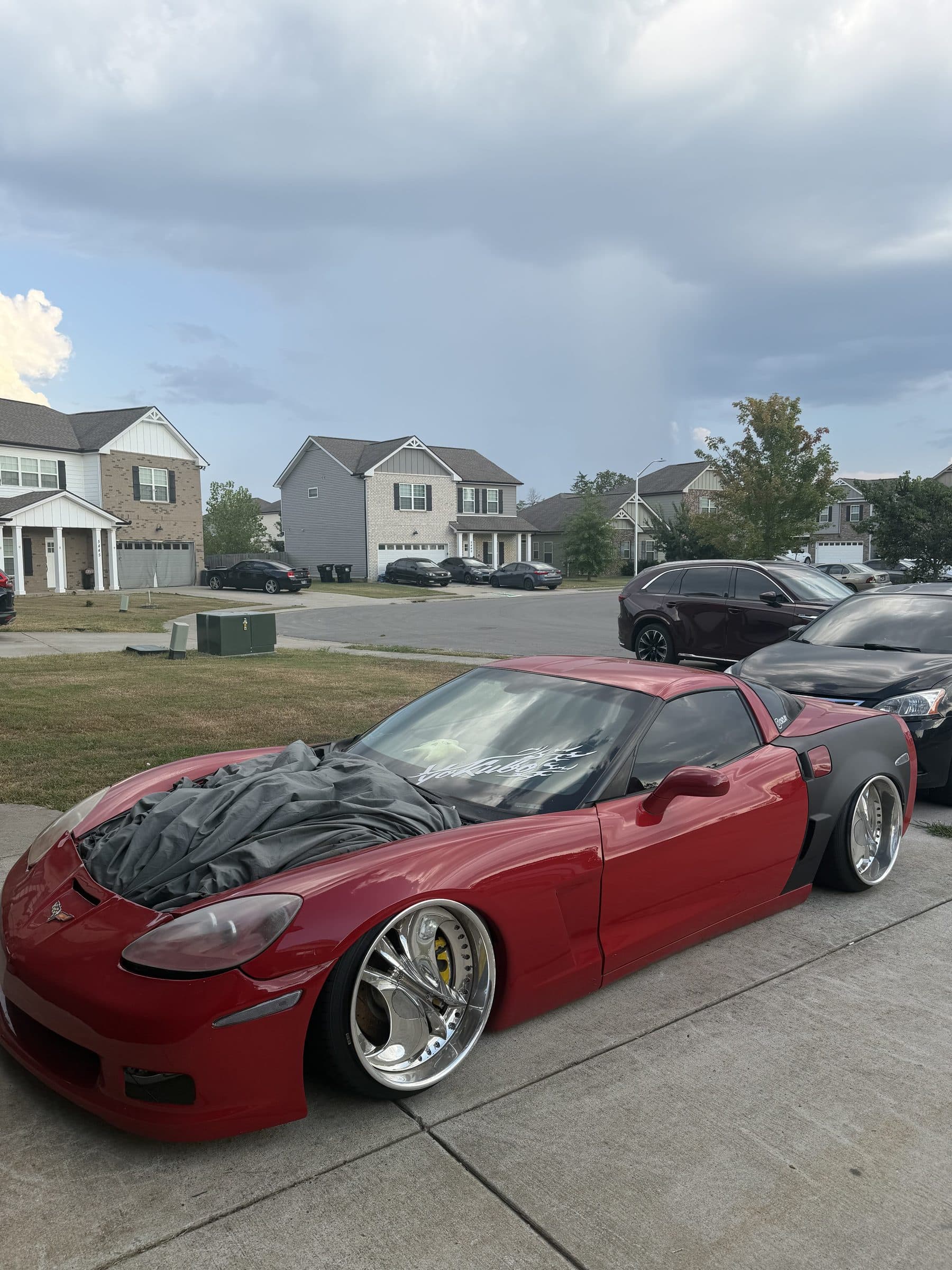 Front three-quarter view of Clayton's red C6 Corvette under a cloudy sky