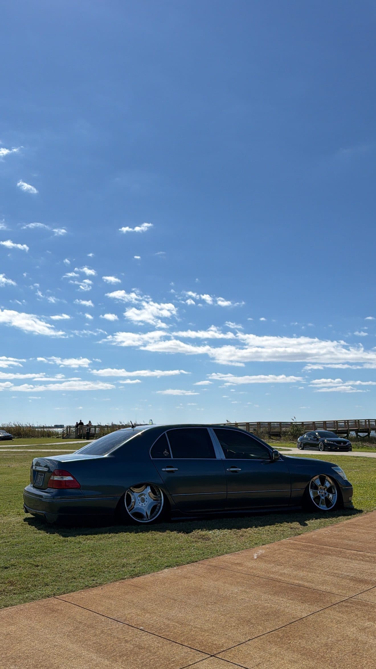 Juan's grey Lexus LS430 on the grass beside a boardwalk under blue sky
