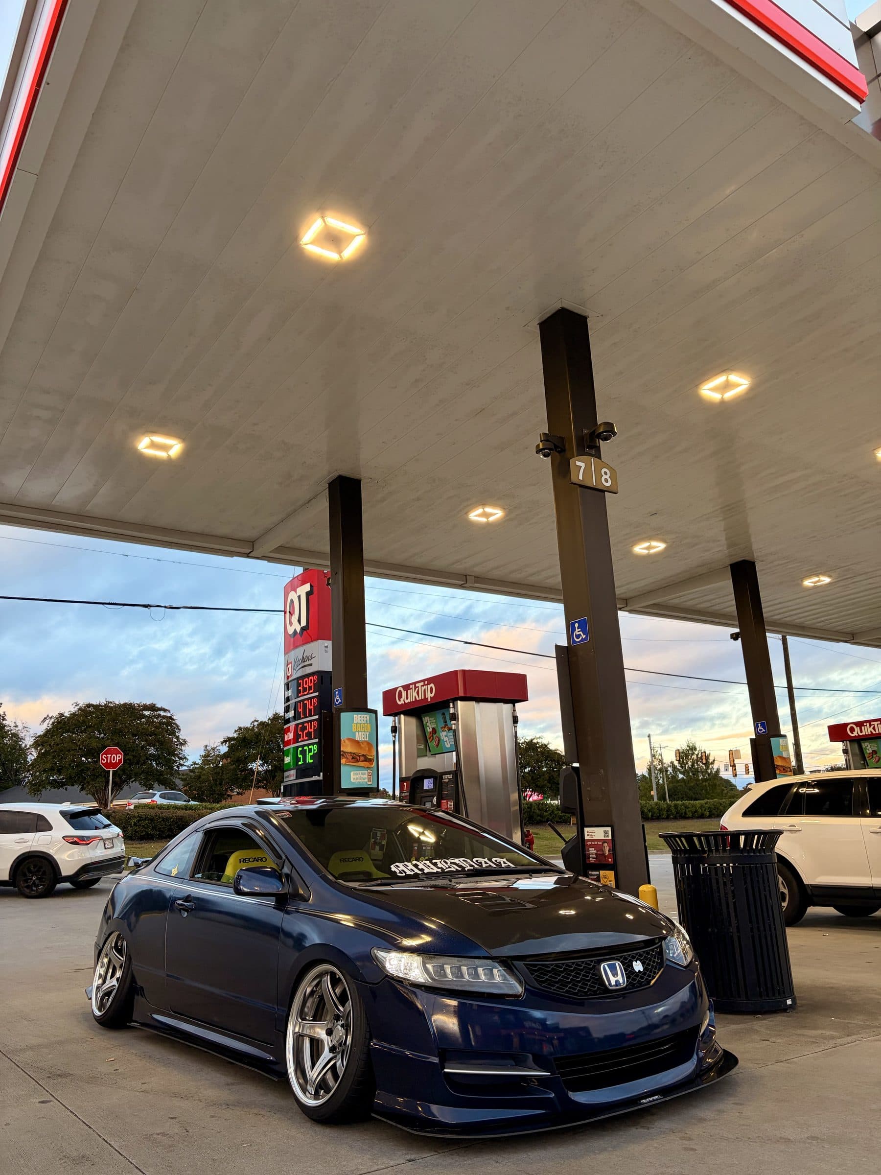 Front three-quarter view of Max's blue Honda Civic coupe at a QuikTrip pump