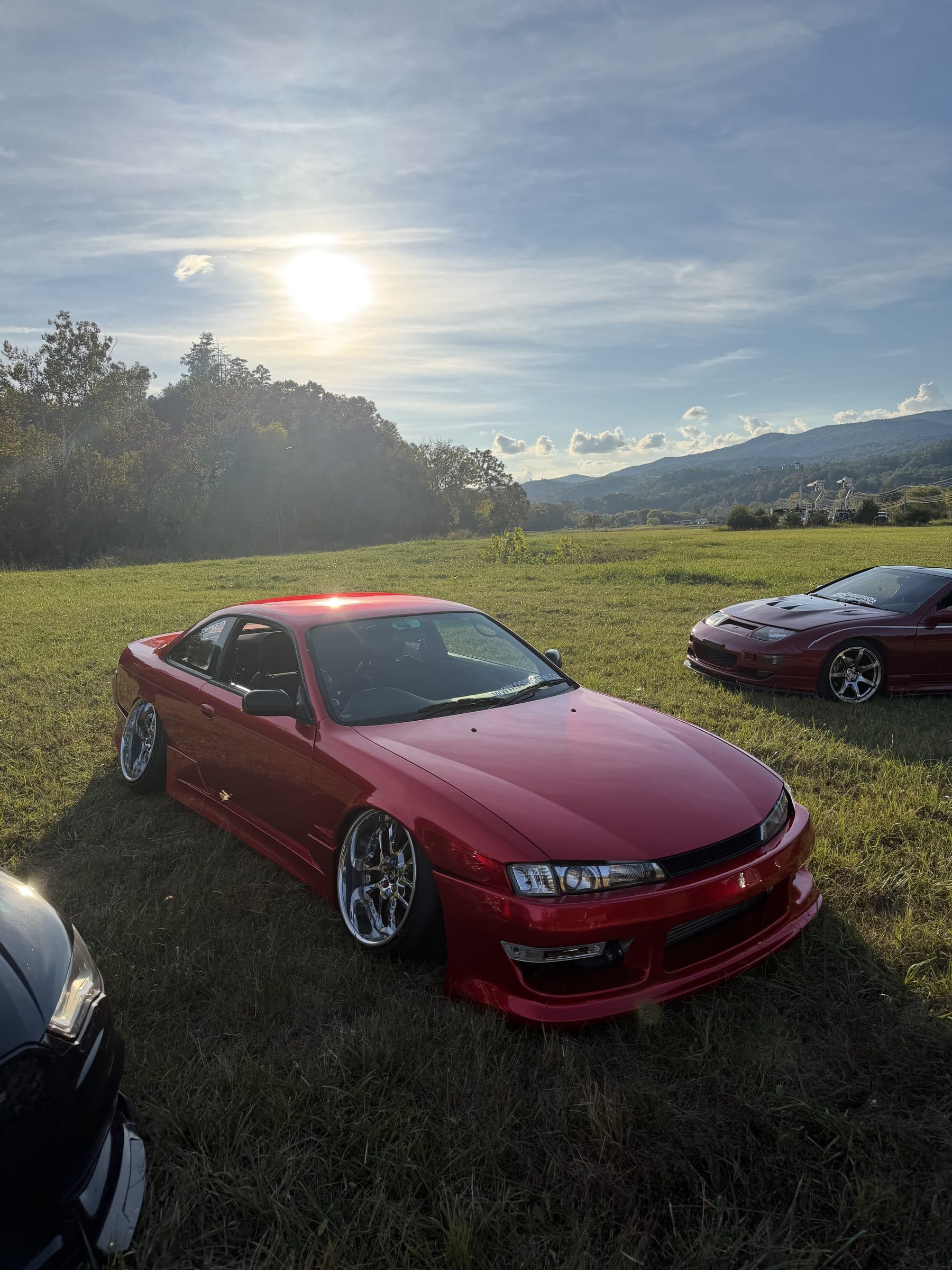 Torres's red Nissan S14 on the grass under a bright sky