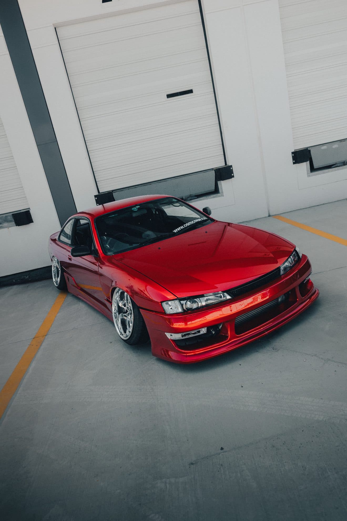 Torres's red Nissan S14 parked in front of a garage door