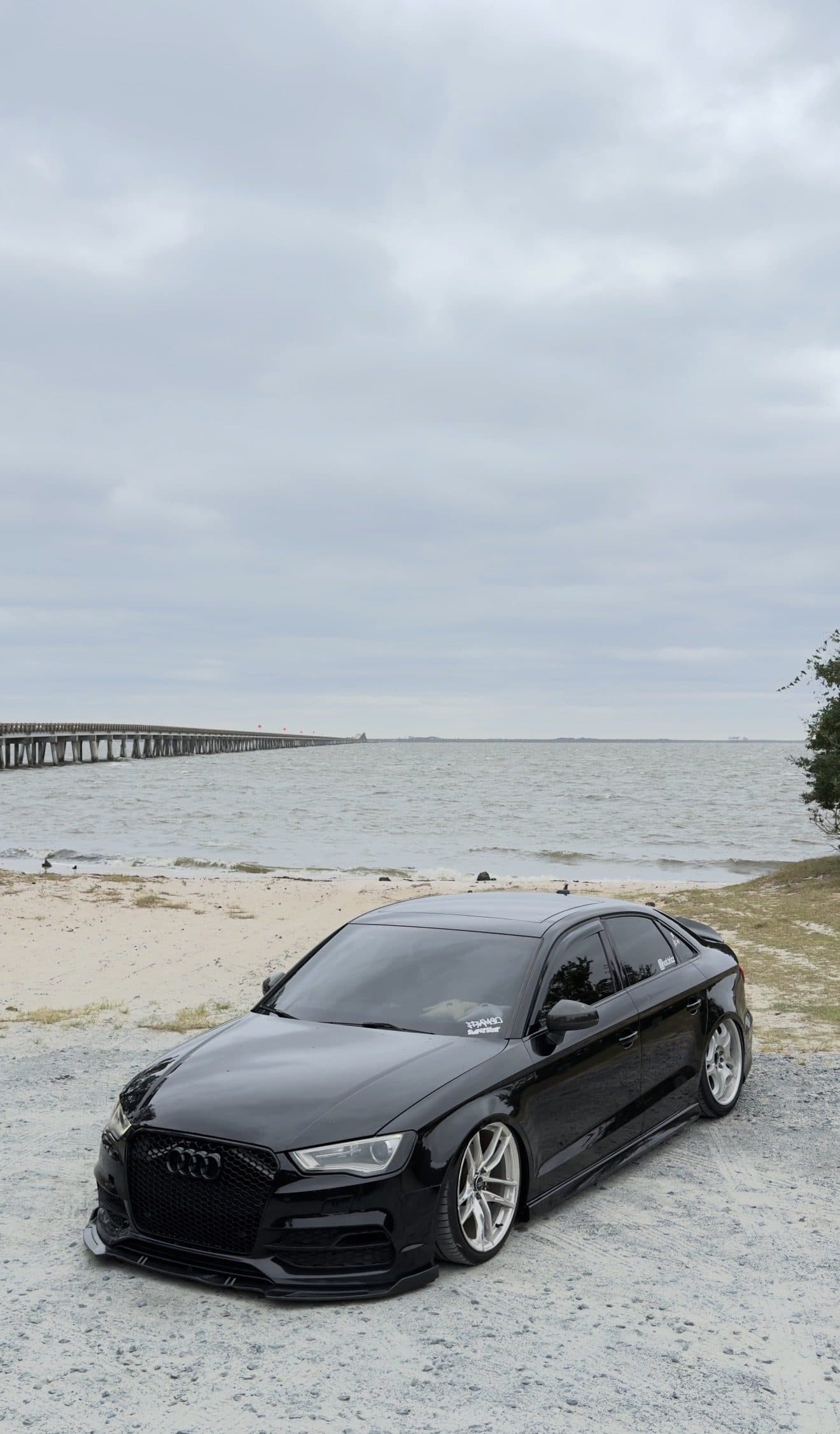 Tristan's black Audi A3 sedan parked on a sandy beach