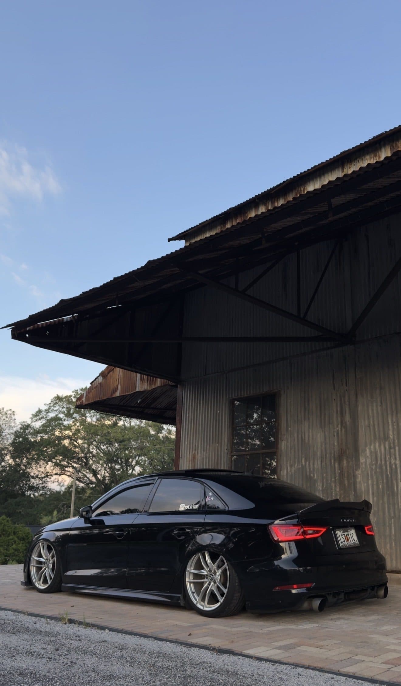 Rear three-quarter view of Tristan's Audi A3 beside an old wooden warehouse