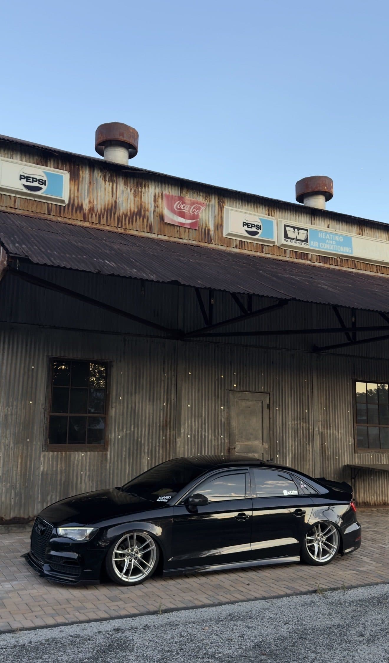Tristan's black Audi A3 in front of a weathered warehouse with vintage signs